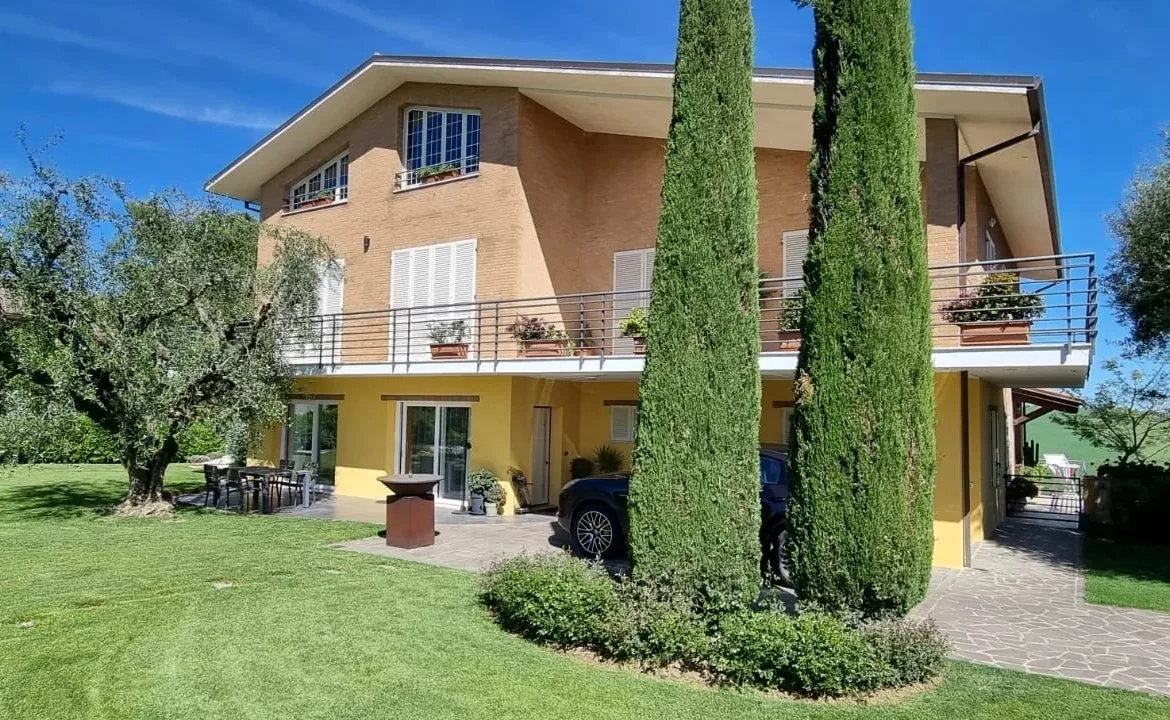 Facciata della villa con i cipressi del giardino.