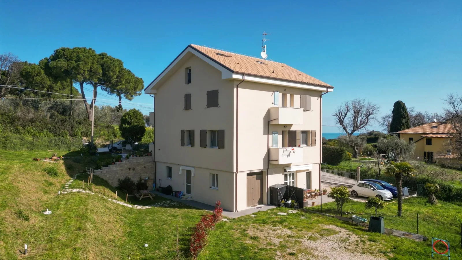 Facciata della villetta tra gli alberi, con vista sul mare.