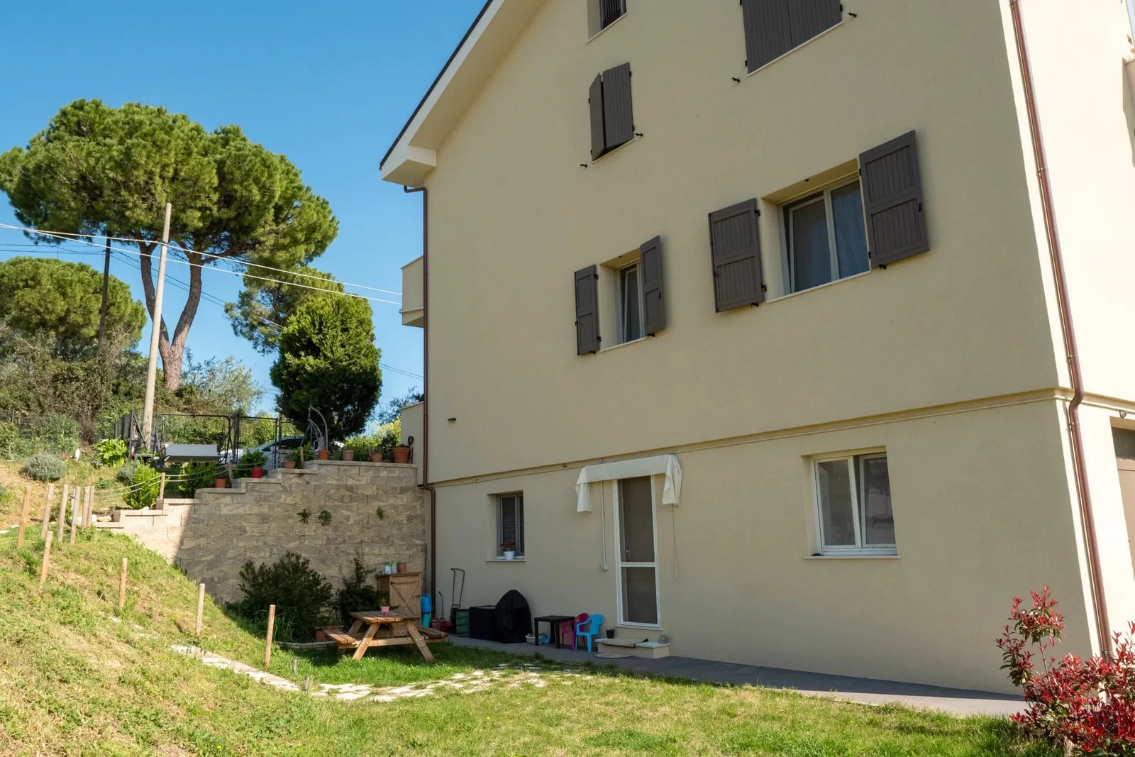 Facciata della villetta con pini nel giardino.