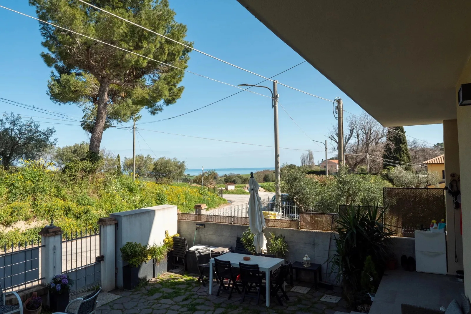 Terrazza con tavolo esterno e vista sul mare in lontananza.