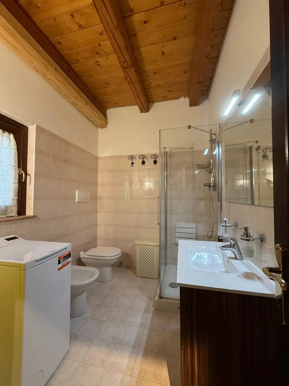 Uno dei due bagni con doccia e soffitto in legno.