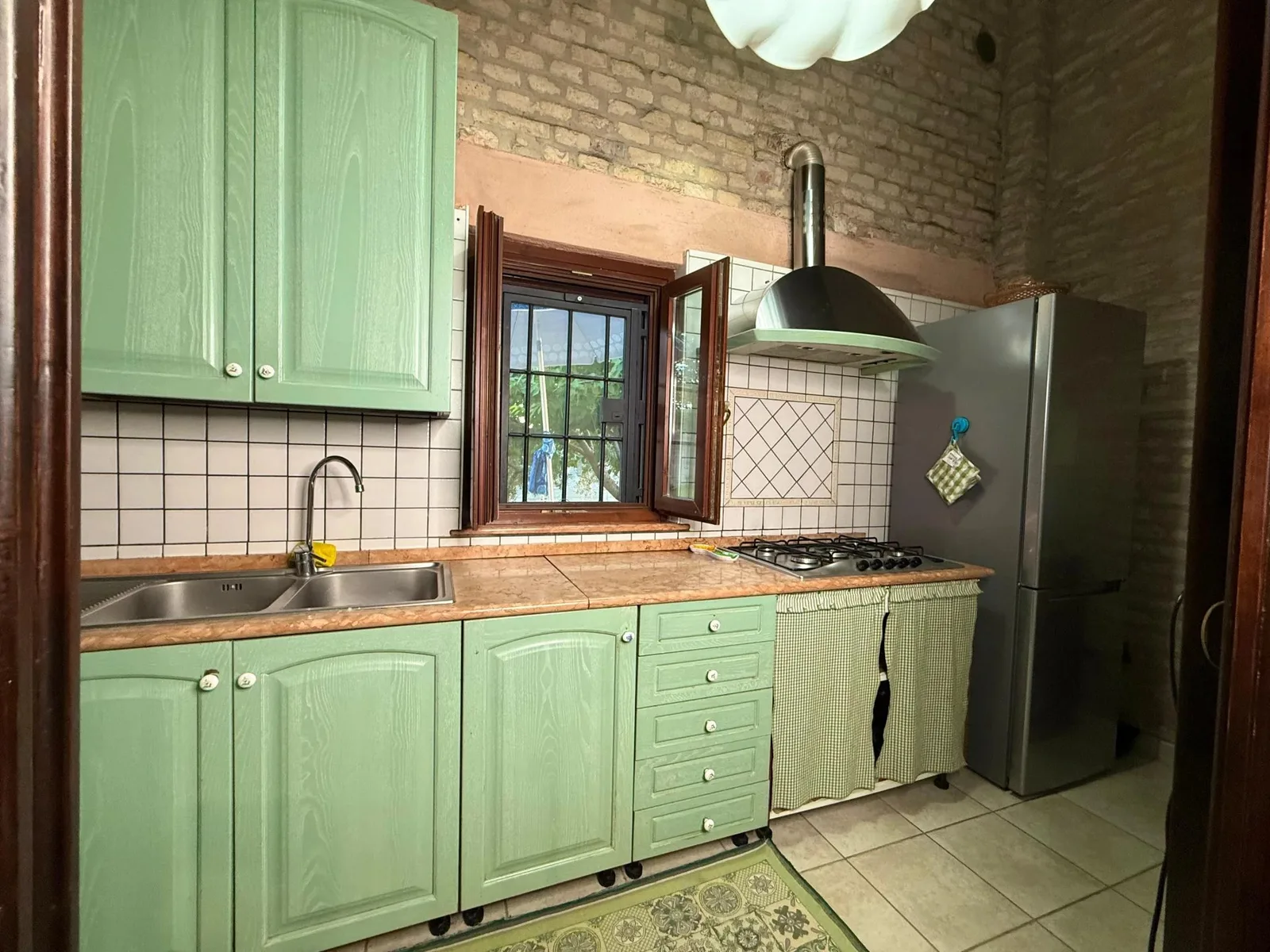 La cucina attrezzata in stile rustico, con pareti in mattone pieno.